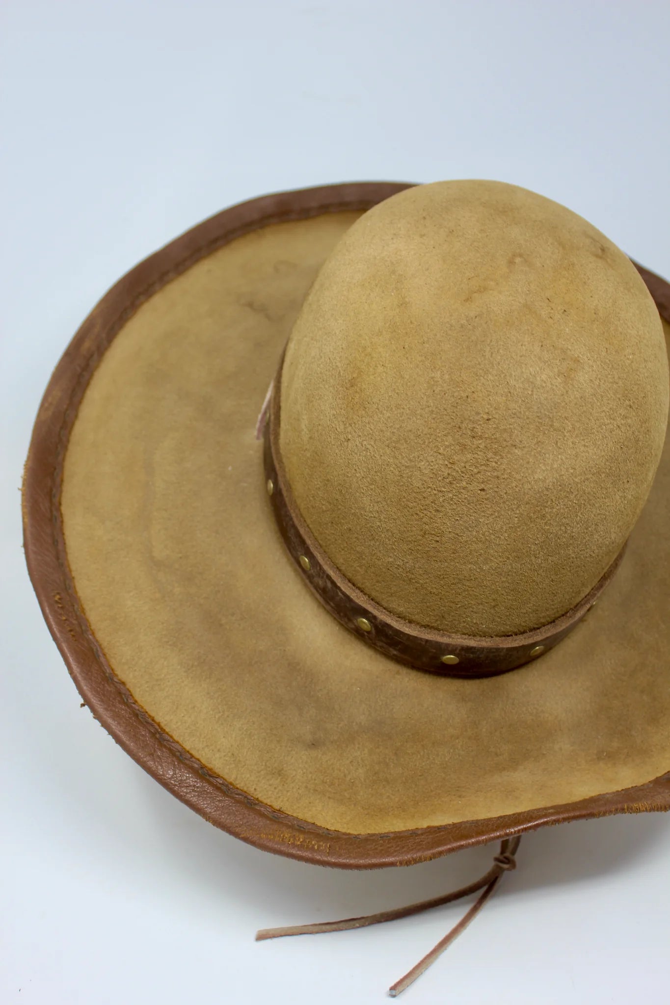 partial top view of Handmade wide brim hat inspired by Elsa “Lightning with the Yellow Hair” from the 1883 series with leather band, studs, and stampede strap.
