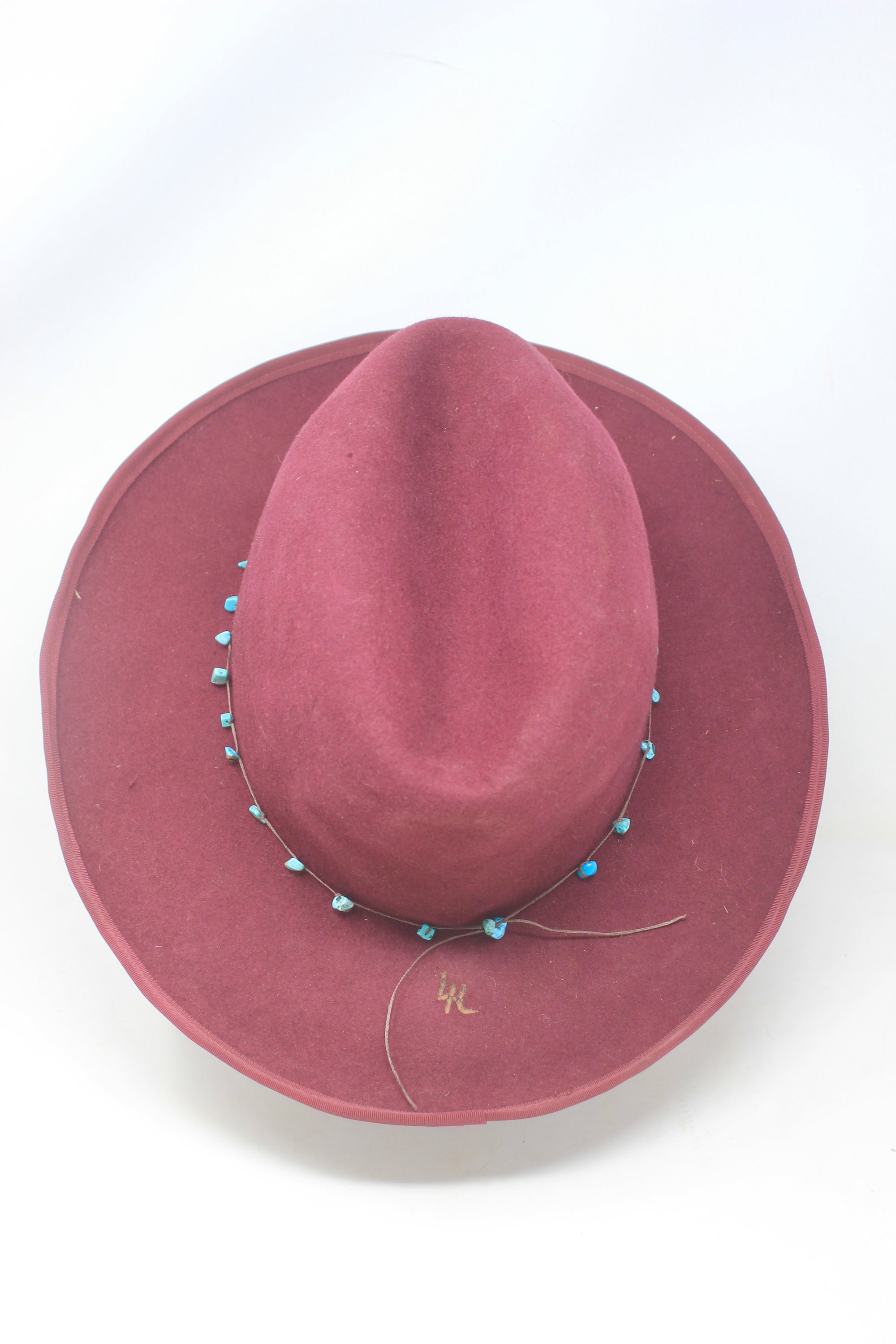 top view of the LH Bordeaux Crease hat by Lone Hawk Hats featuring bordeaux fur blend felt, a slight crease crown, and a hand-tied turquoise band, size 7 1/4.