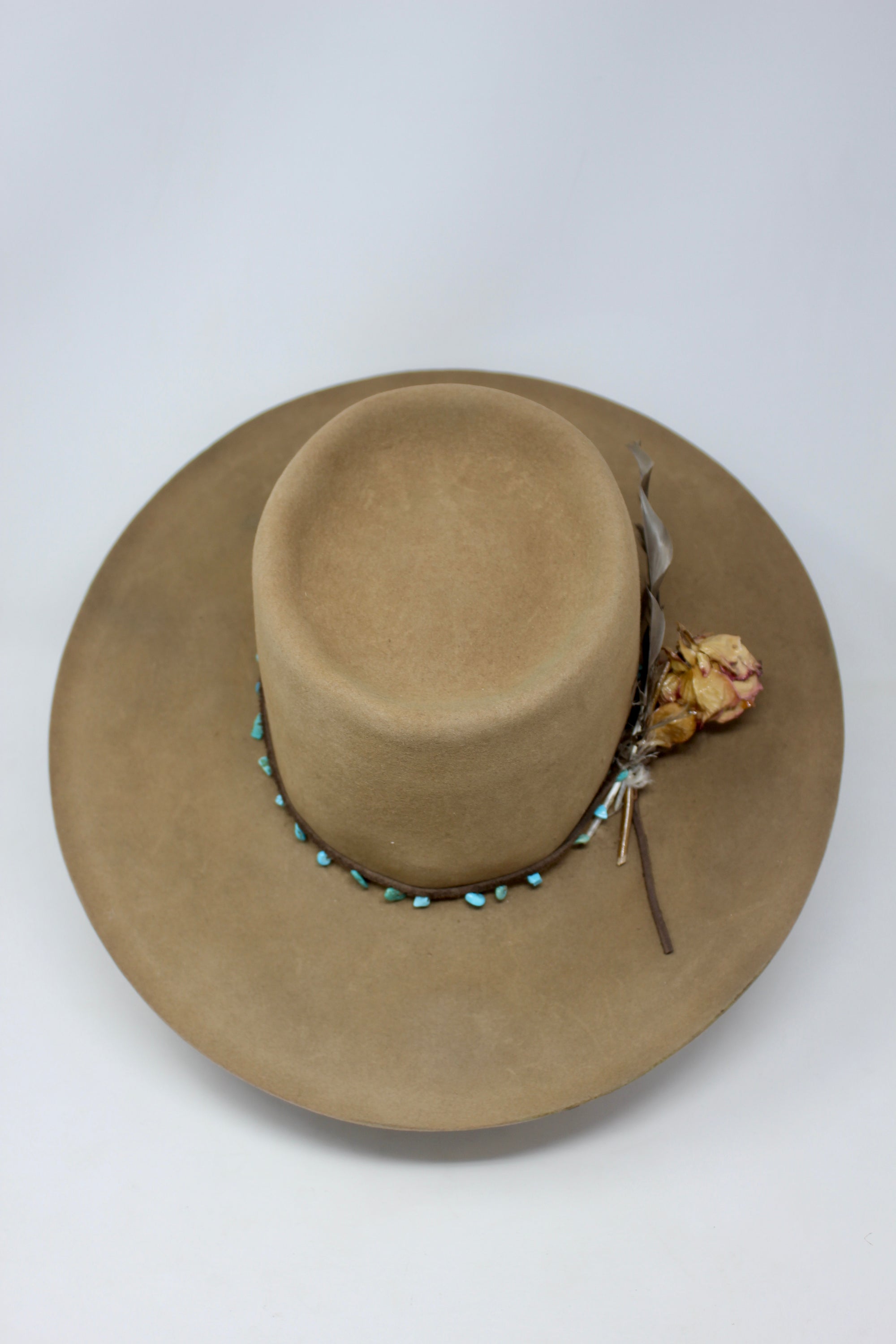 Top view of Tele Top Camel hat by Lone Hawk Hats featuring a dipped telescope crown, wider brim, hand-knotted turquoise band, sterling hawk pin, and found feather accent.