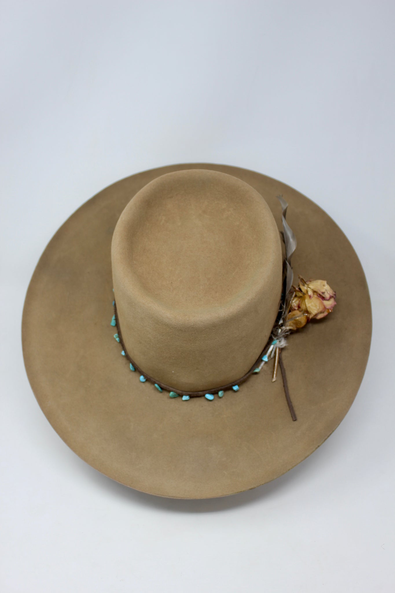 Top view of Tele Top Camel hat by Lone Hawk Hats featuring a dipped telescope crown, wider brim, hand-knotted turquoise band, sterling hawk pin, and found feather accent.