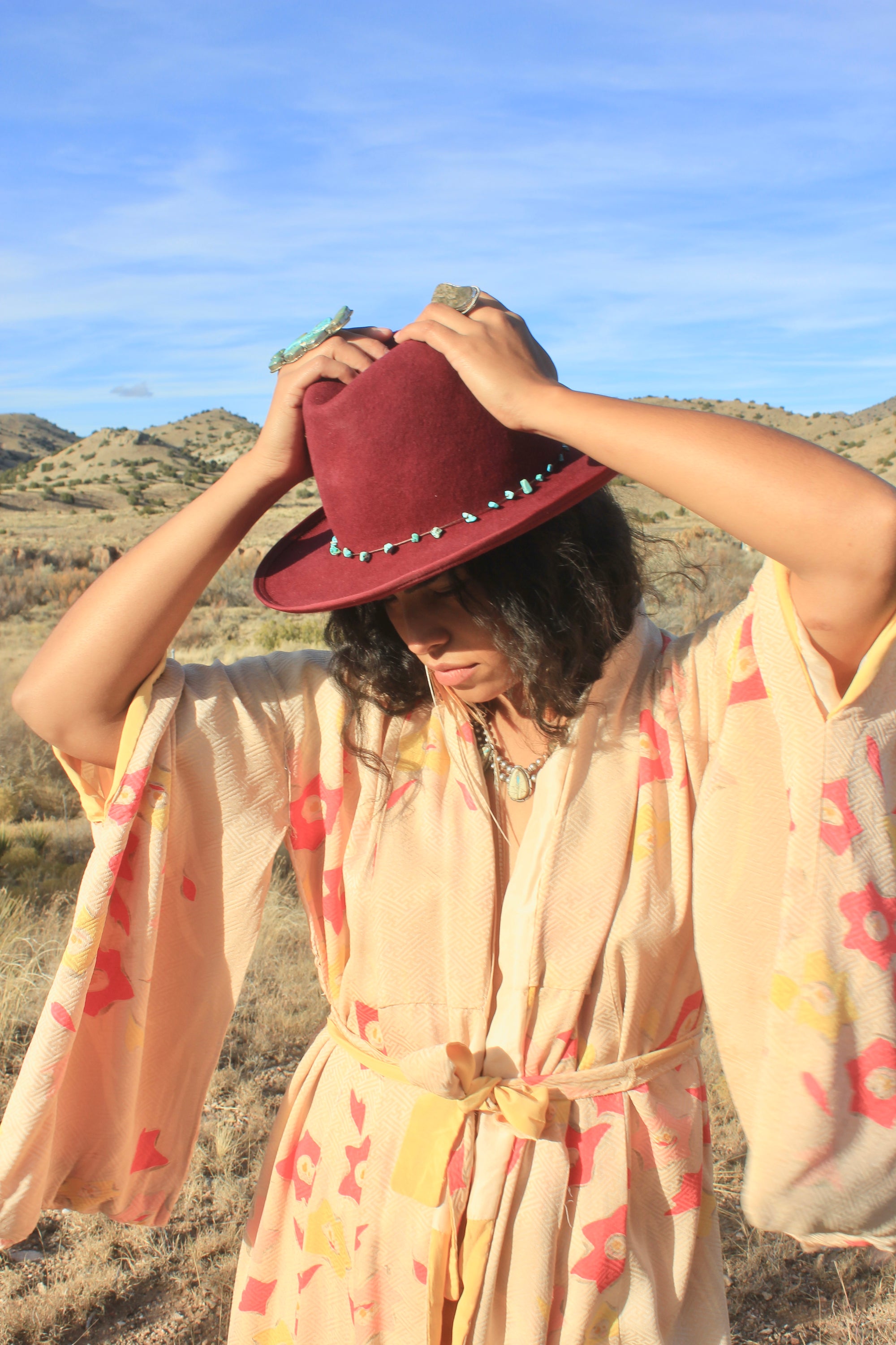 Woman holding the LH Bordeaux Crease hat by Lone Hawk Hats featuring bordeaux fur blend felt, a slight crease crown, and a hand-tied turquoise band, size 7 1/4.