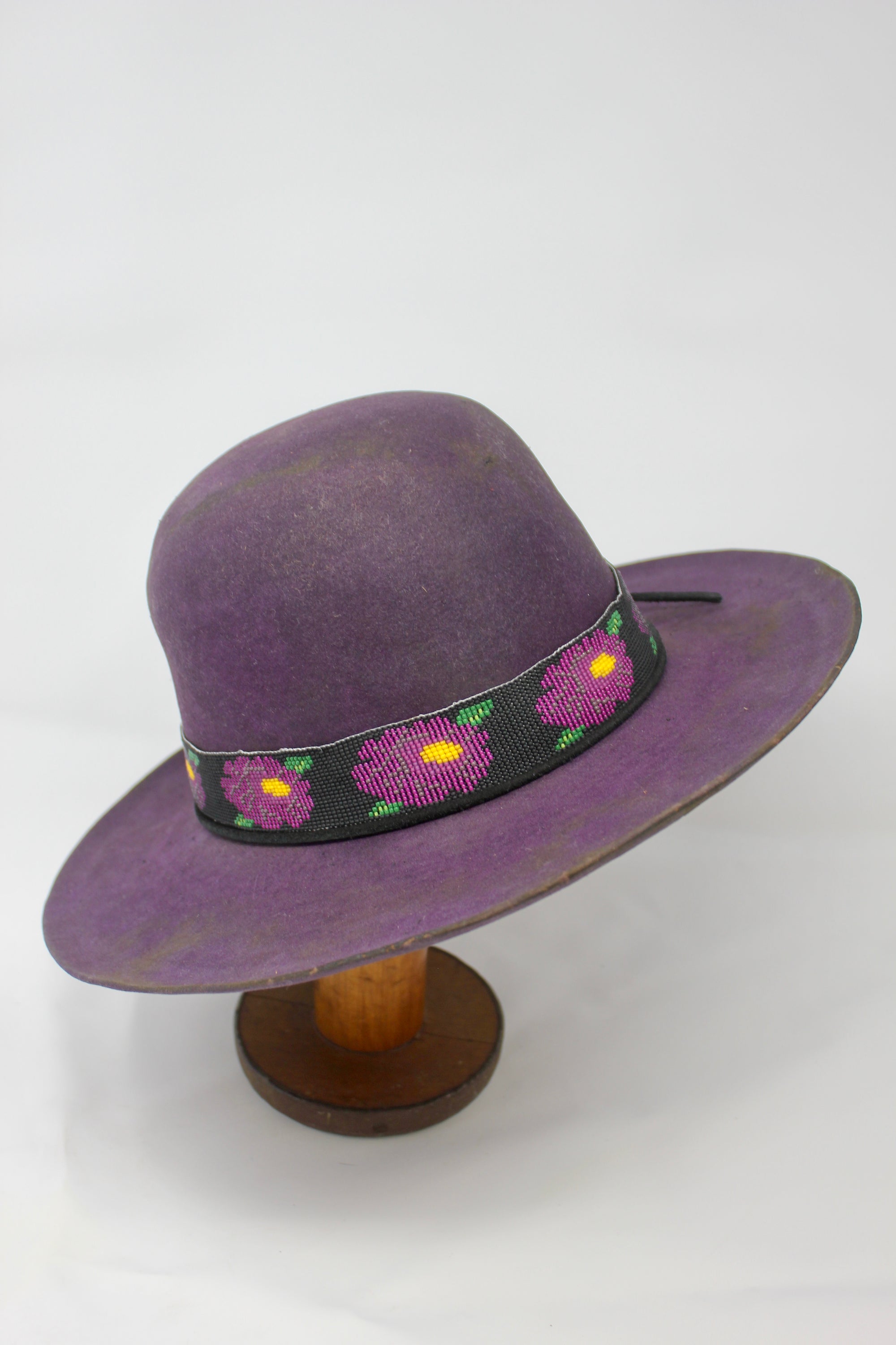 Front right view of the Plum Crazy hat by Lone Hawk Hats featuring hand-dyed purple vintage beaver felt, an open crown, and a hand-beaded floral band.