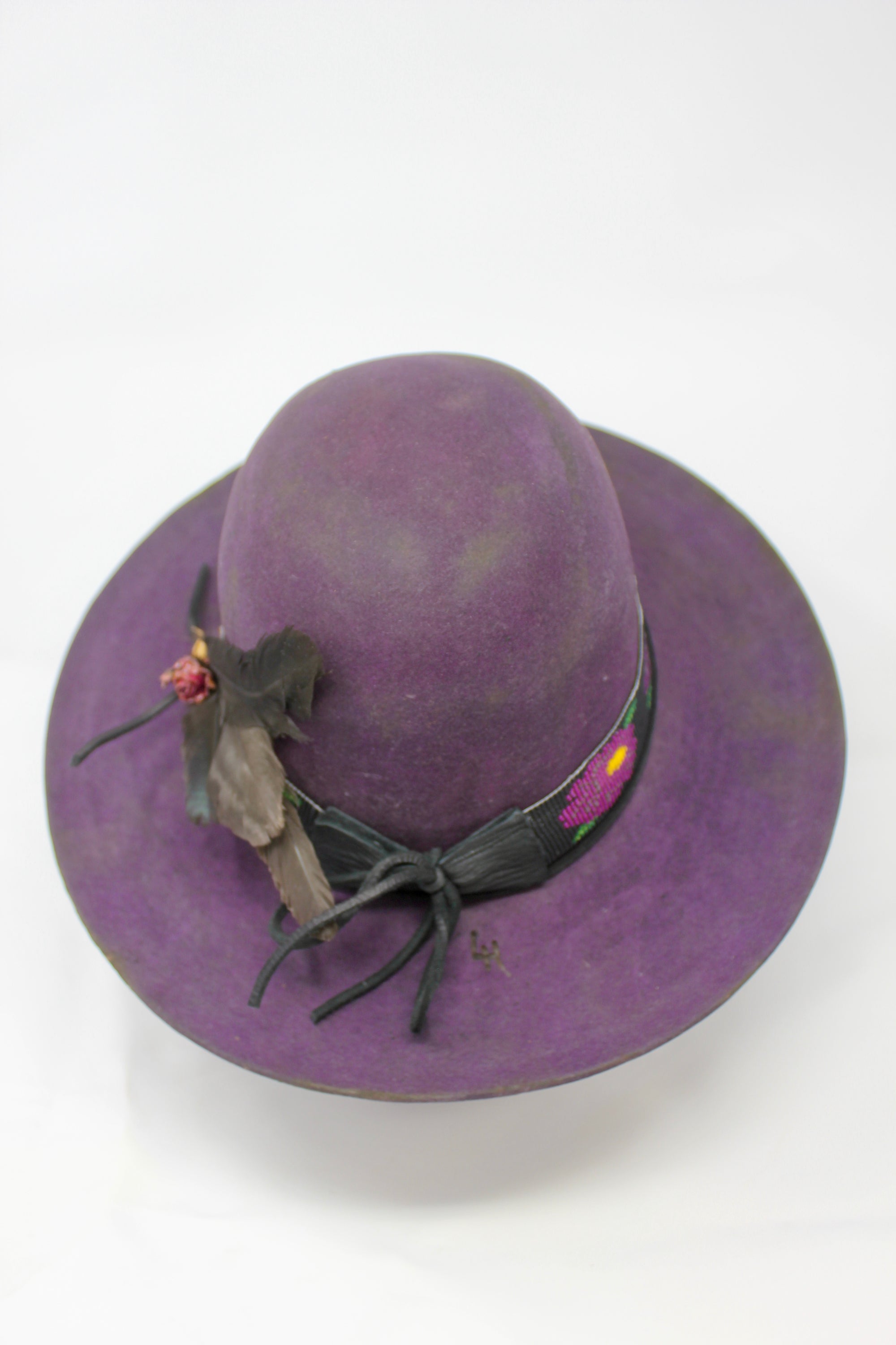 top view of  the Plum Crazy hat by Lone Hawk Hats featuring hand-dyed purple vintage beaver felt, an open crown, and a hand-beaded floral band.