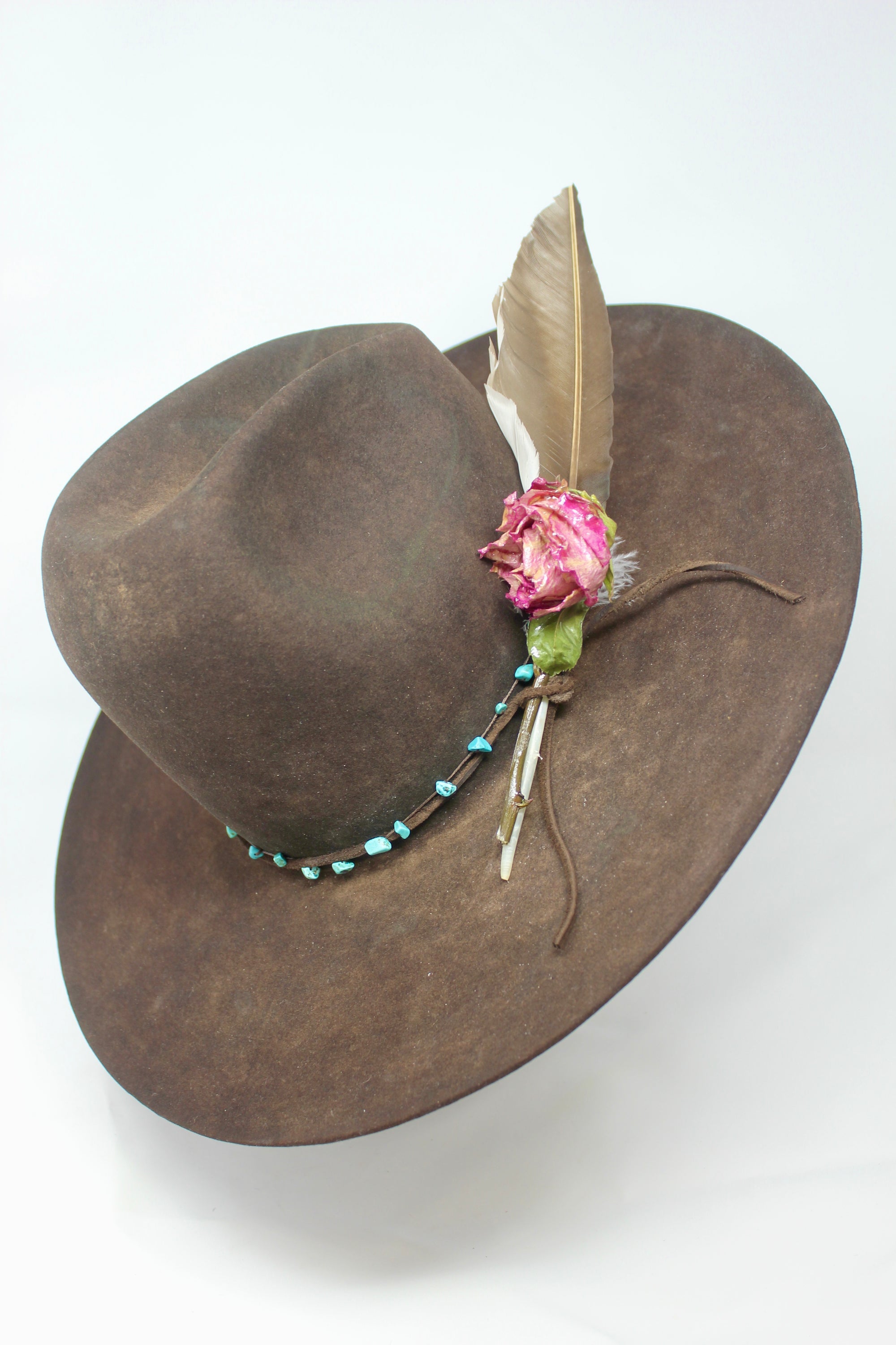 Left view of the Lone Hawk wide brim tall crown western hat in vintage beaver felt featuring a hand-tied turquoise band, dried rose accent, and high-front low-back shaping.
