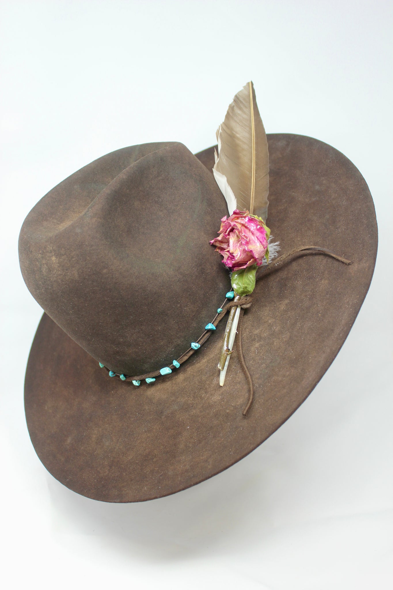 Left view of the Lone Hawk wide brim tall crown western hat in vintage beaver felt featuring a hand-tied turquoise band, dried rose accent, and high-front low-back shaping.