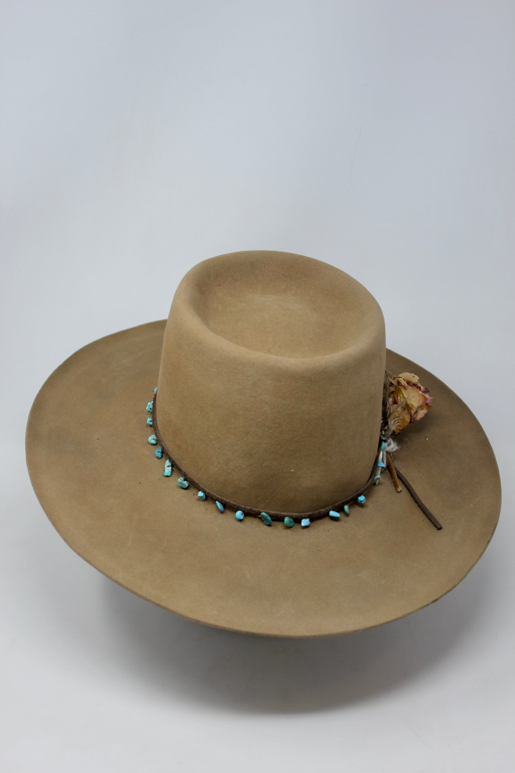 Front of the Tele Top Camel hat by Lone Hawk Hats featuring a dipped telescope crown, wider brim, hand-knotted turquoise band, sterling hawk pin, and found feather accent.