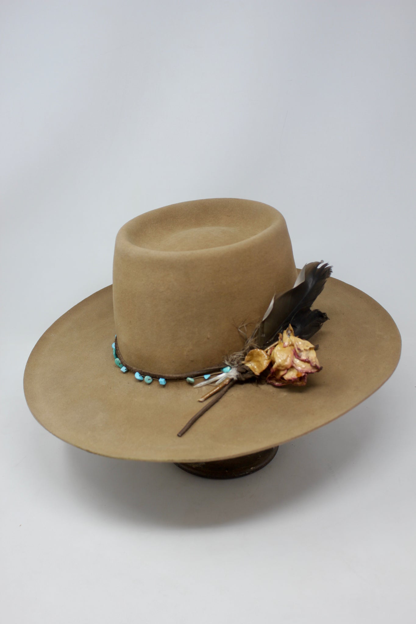 Left view of the Tele Top Camel hat by Lone Hawk Hats featuring a dipped telescope crown, wider brim, hand-knotted turquoise band, sterling hawk pin, and found feather accent.
