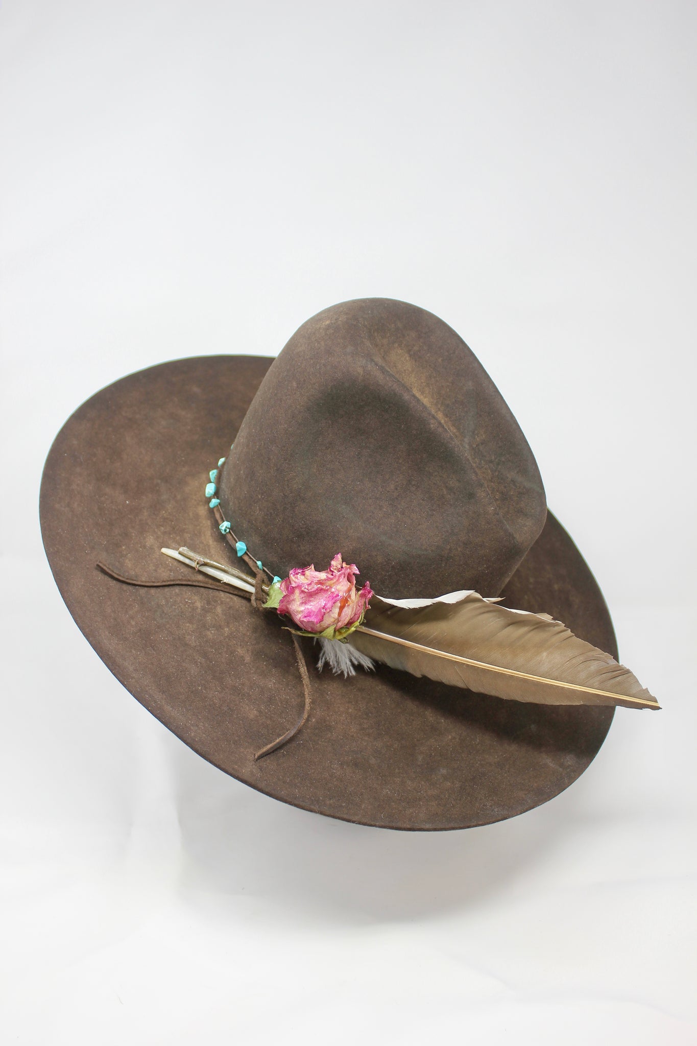 Left view of Lone Hawk wide brim tall crown western hat in vintage beaver felt featuring a hand-tied turquoise band, dried rose accent, and high-front low-back shaping.