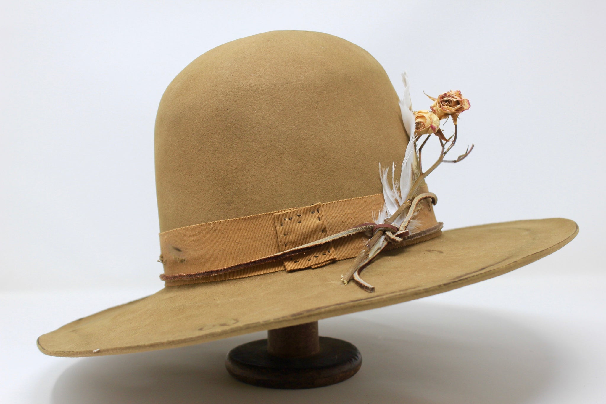 Left view of the Cree Mountain hat by Lone Hawk Hats featuring a tall open crown, flat brim with a slight pencil roll, hand-sewn band, feather accents, and light distressing.