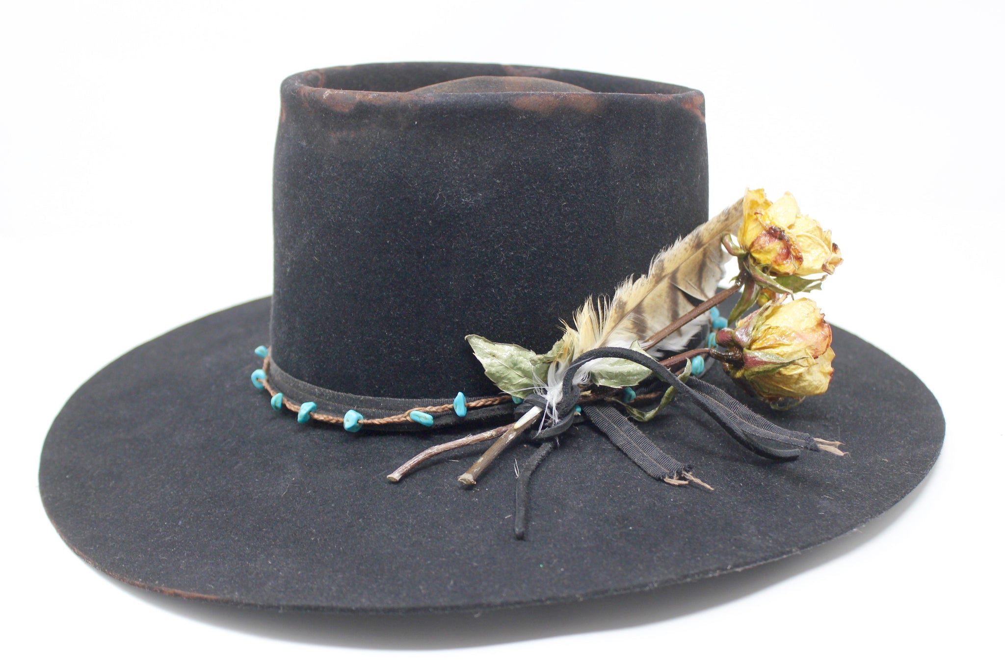 Left view of The Horse Thief Badlands custom Lone Hawk hat featuring a distressed telescope crown, wide flat brim, turquoise embellishment, and found feather detail, handcrafted in California.