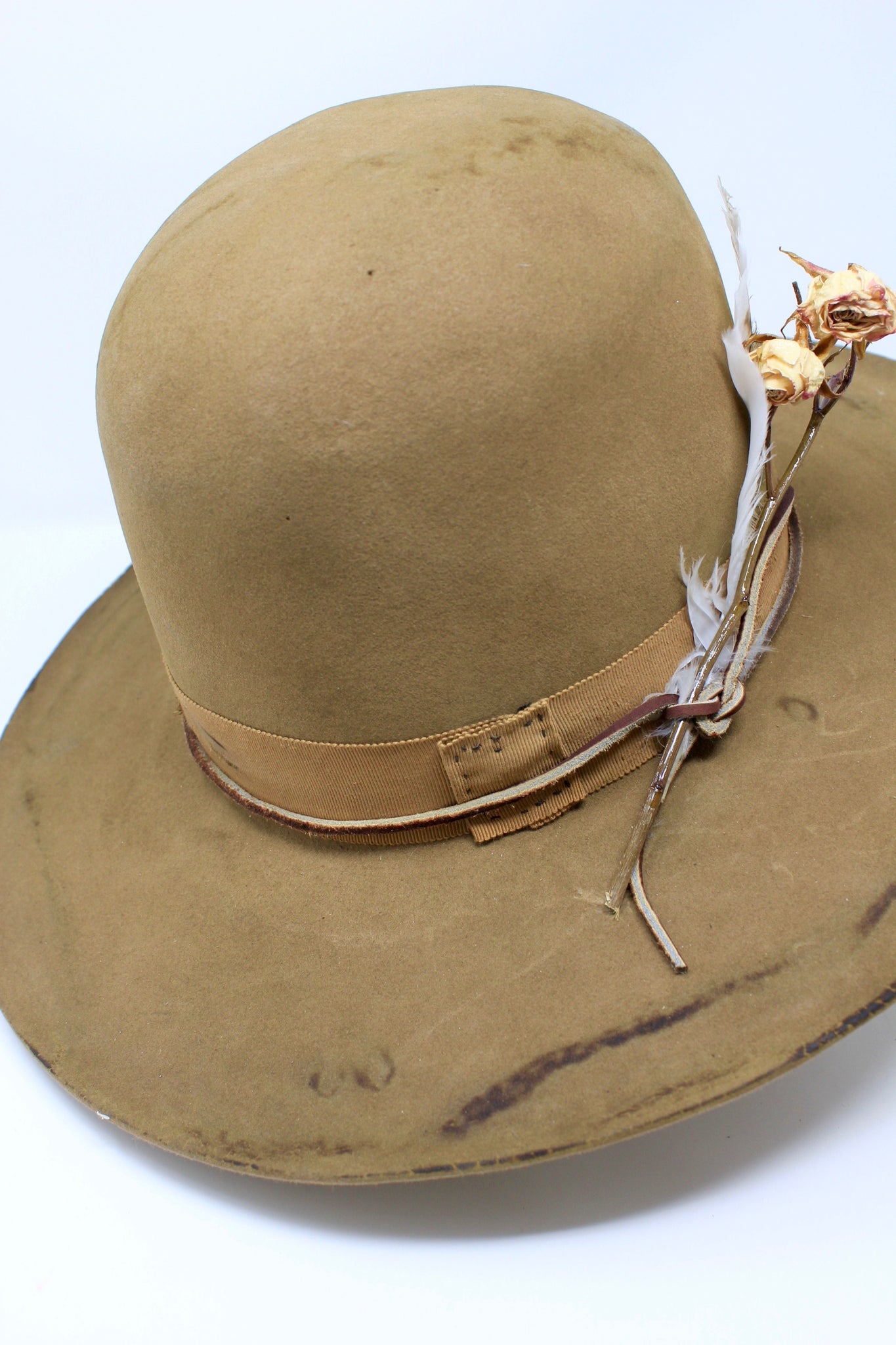top left view of the Cree Mountain hat by Lone Hawk Hats featuring a tall open crown, flat brim with a slight pencil roll, hand-sewn band, feather accents, and light distressing.