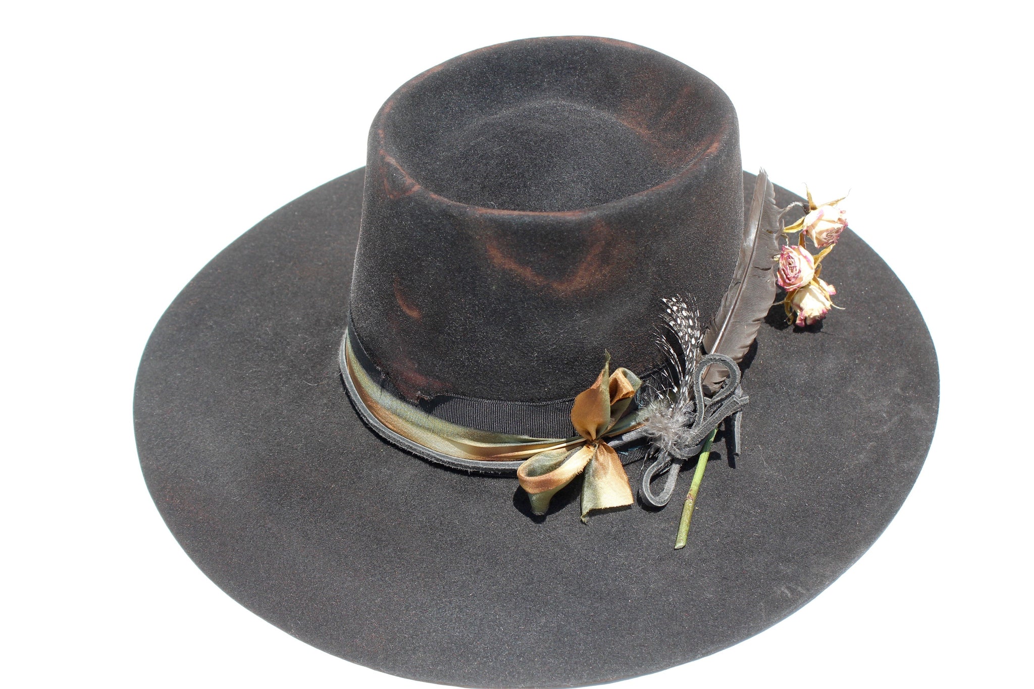 top left view of The Emerald Hawk by Lone Hawk Hats, a distressed telescope crown western hat featuring a wide flat brim with Bardot dip, hand-dyed silk ribbon, dried flowers, and found feathers.