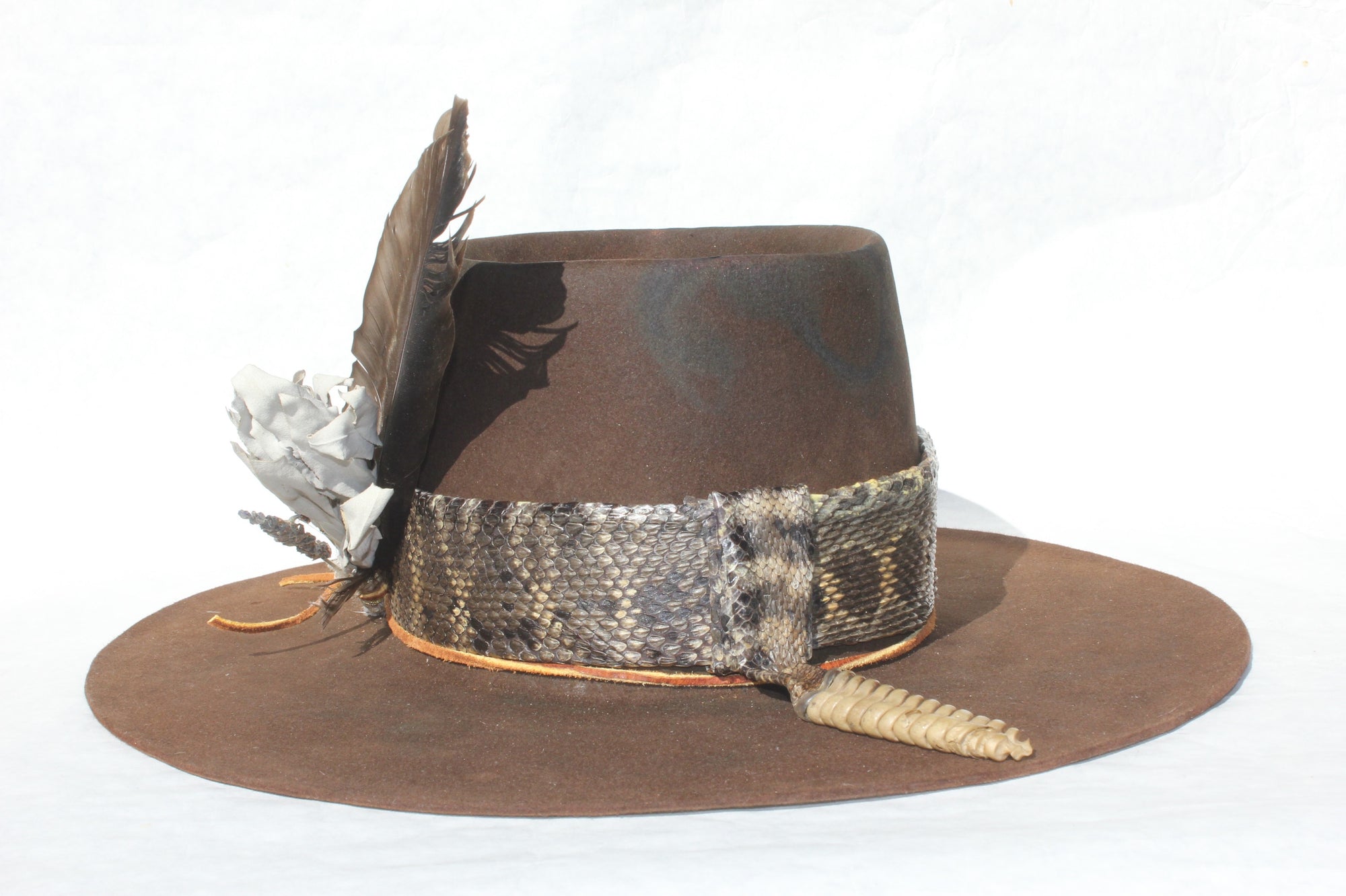 Right side of The Snakebite Telle custom Lone Hawk hat featuring a telescope crown, flat brim, beaver felt body, custom rattlesnake skin band, and found feather accent.ght 