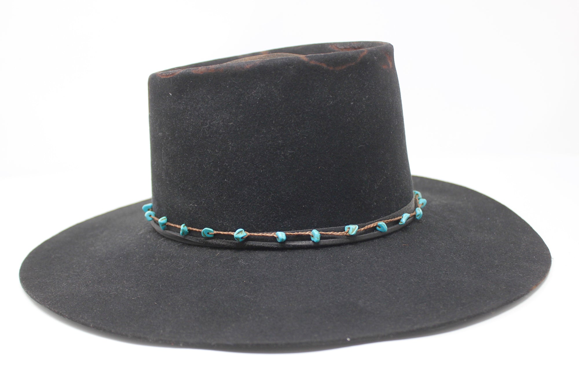 Right view of The Horse Thief Badlands custom Lone Hawk hat featuring a distressed telescope crown, wide flat brim, turquoise embellishment, and found feather detail, handcrafted in California.