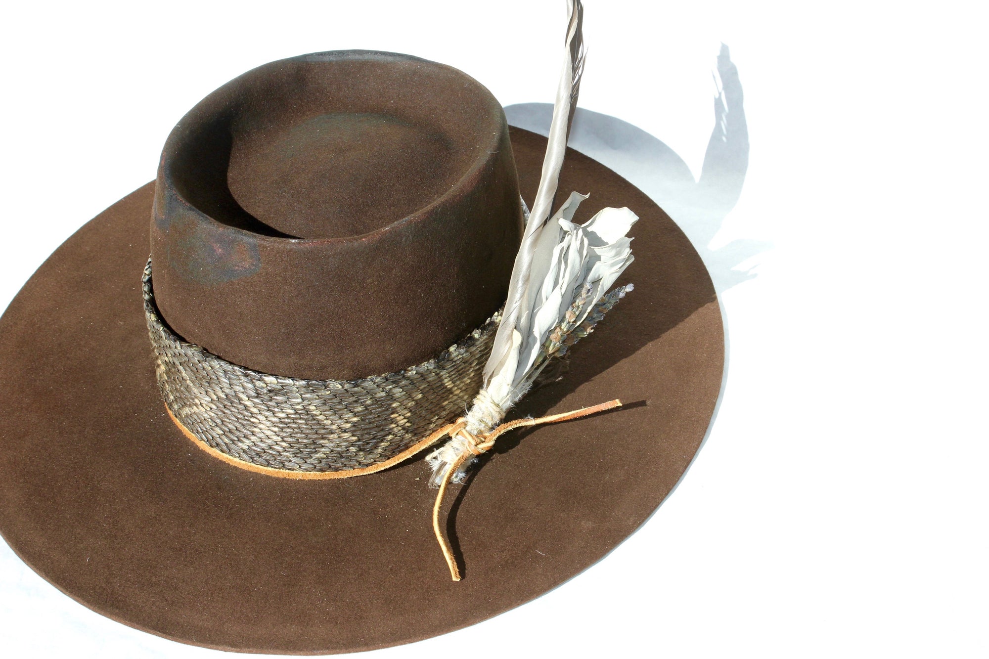 Top view of The Snakebite Telle custom Lone Hawk hat featuring a telescope crown, flat brim, beaver felt body, custom rattlesnake skin band, and found feather accent.