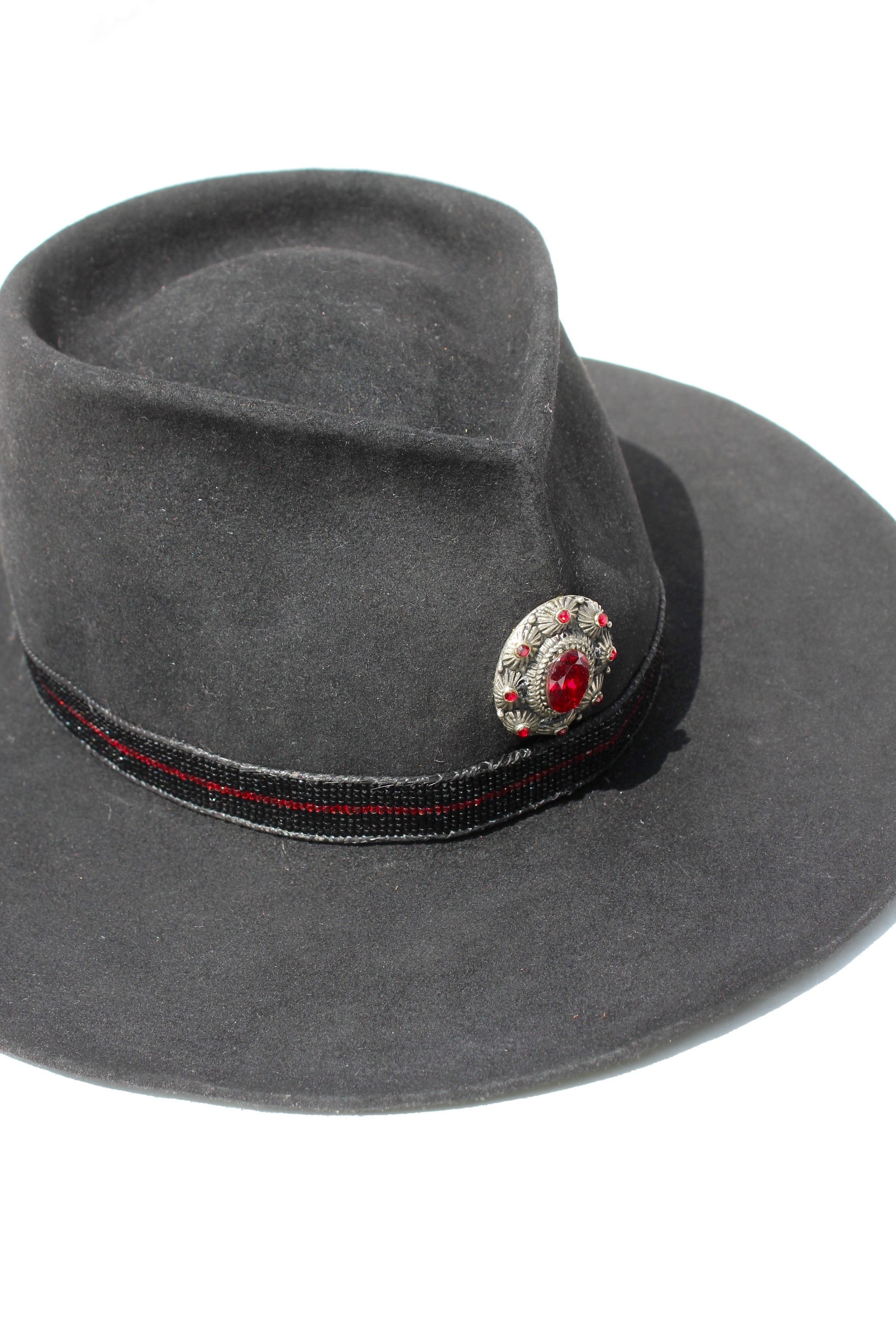 Close up view of the medaillon on The Saturday Night Fever custom Lone Hawk hat, a handmade beaver fur blend western hat featuring a tall tear-drop crown, hand-beaded band with horsehair detail, and antique English medallion.